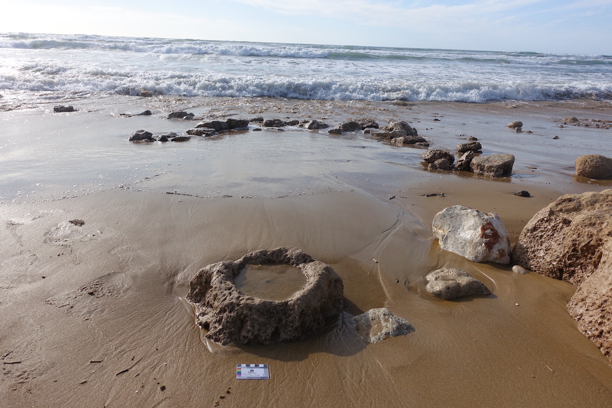 Coastal erosion in Tel Hreiz and the exposure of site features: a stone bowl and a wall segment.